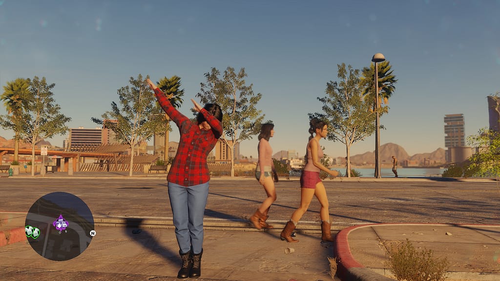 Image Descriptor: A screenshot of Saints Row 2022. My character, dressed in a red flannel shirt and blue jeans, dabs by the side of the street as two women walk by.