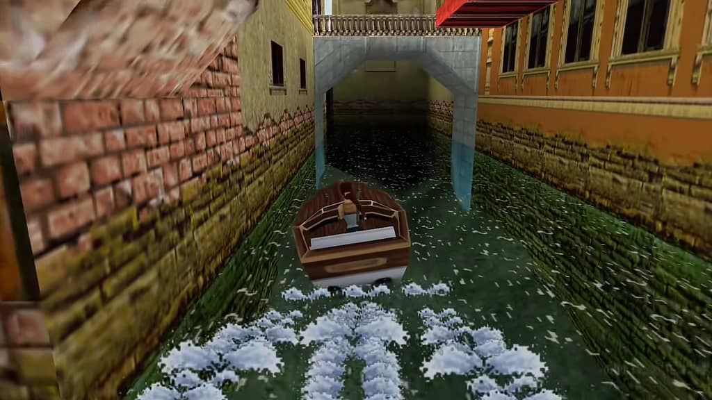Image descriptor: Lara Croft is riding a motorboat through the canals of Venice, surrounded by several buildings either side, coloured various shades of yellow and brown. A distinct bridge stands up ahead.