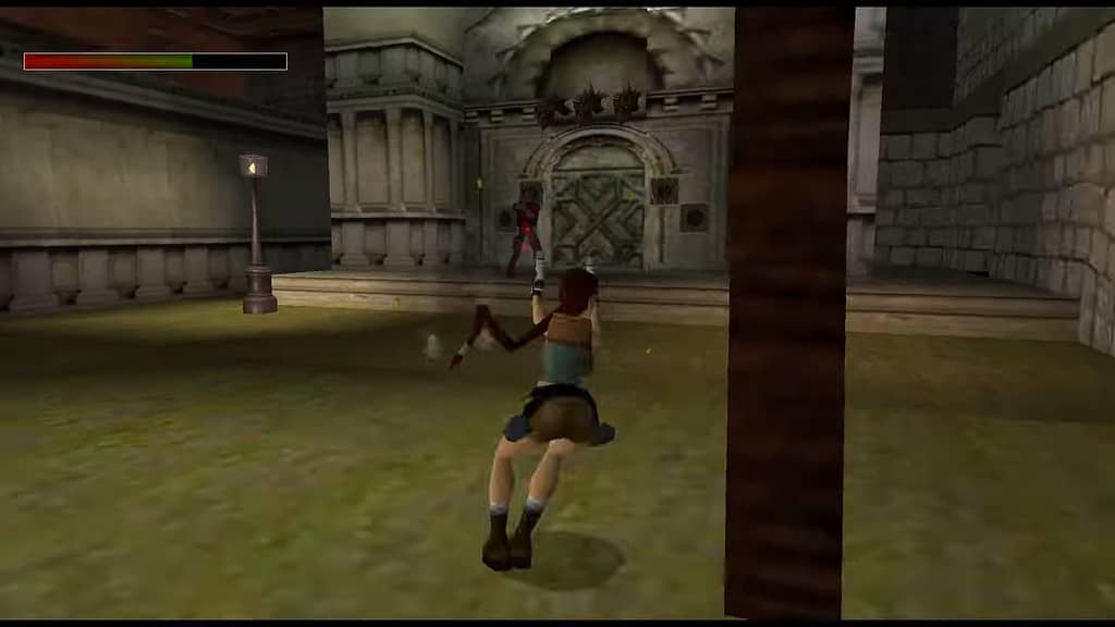 Image Descriptor: Lara lands from a sideways somersault as she shoots at a distant enemy. The fight takes place outside the entrance to a tomb in Rome, upon a small grassy patch of land.