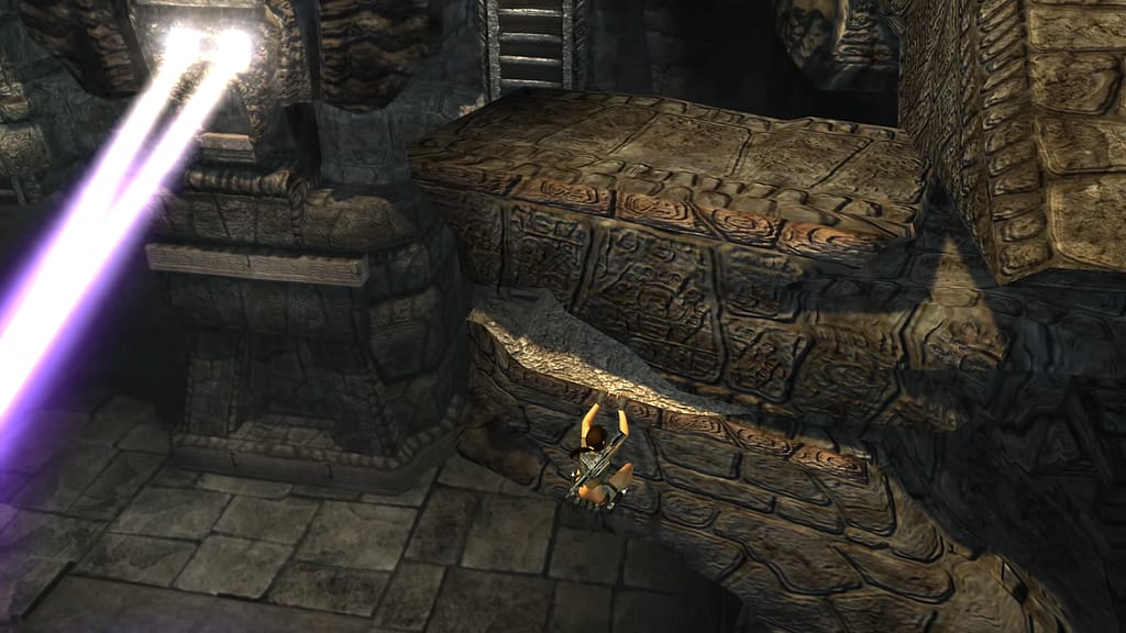 Image Descriptor: Lara clings onto the side of a broken ledge, within some Peruvian ruins. The upper section of a ladder can be seen in the top centre, whilst a large statue on the left projects two beams of light from its eyes.